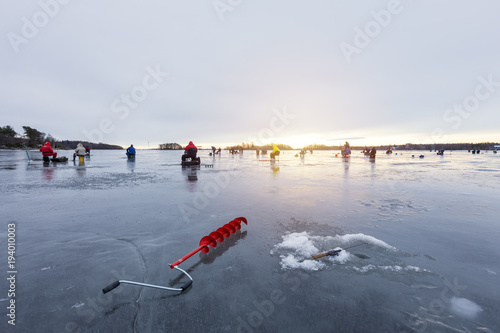 Group of fishermens on winter fishing on ice at sunset