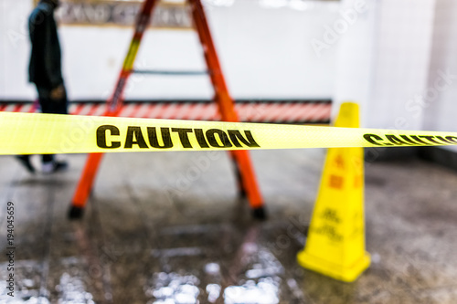 Caution tape sign in underground transit empty large platform in New York City NYC Subway Station in Grand Central, ladder, wet floor cone