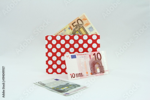 Banknoty EURO w czerwonej kopercie w białe kropki