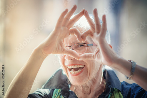 Cute senior old woman making a heart shape with her hands and fingers