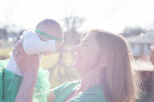 mother holding baby up in bright sunlight