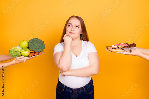 Young woman making choice between healthy and unhealthy food