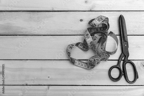 old tailors scissors and meter on a wooden table. black and white photo