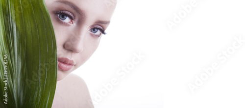 Beauty shoot. European, young, blue-eyed woman posing with fresh, green leaf.