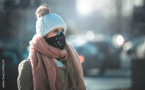 Young woman wearing protective mask in the city street, smog and air pollution