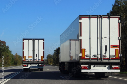 Two trucks on the road in summer against the blue sky