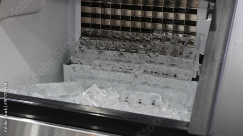 cube ice in ice making machine that door open ; to transform liquid water to solid ice below zero degree celsius ; food and drink industrial background ; close up