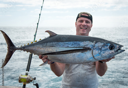 Happy angler holding big tuna fish