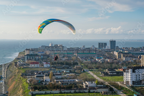 Flying tandem paragliders over the city on a Sunny day