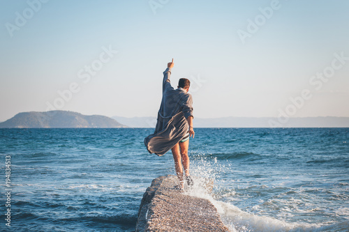 Happy young man dancing on the dock at the beach