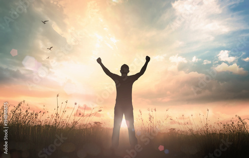 International human rights day concept: Silhouette of man raised hands at sunset meadow