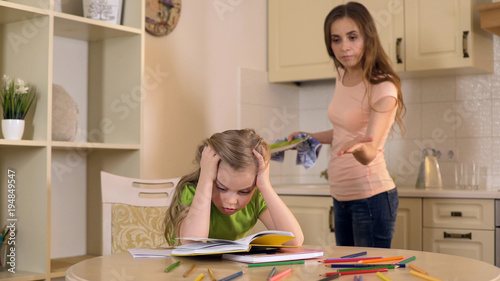 Strict mother criticizing daughter for mistakes in homework, lack of support