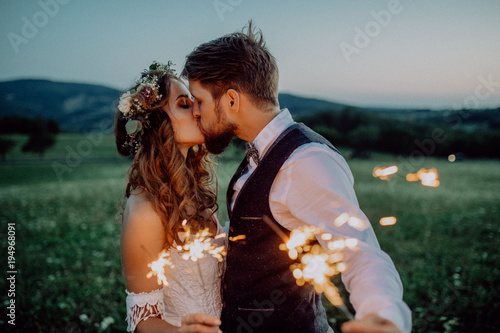 Beautiful bride and groom with sparklers on a meadow.