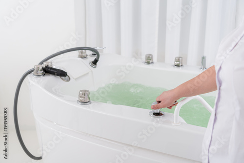 cropped shot of spa salon assistant regulating water in hydro bath