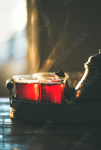 Freshly brewed traditional black tea in turkish tukip glasses and teapot in oriental tray, selective focus, copy space