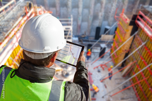 civil engineer or architect on construction site checking schedule with tablet computer