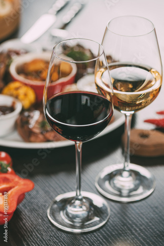 close-up view of glasses of wine and plate with grilled vegetables and meat on table