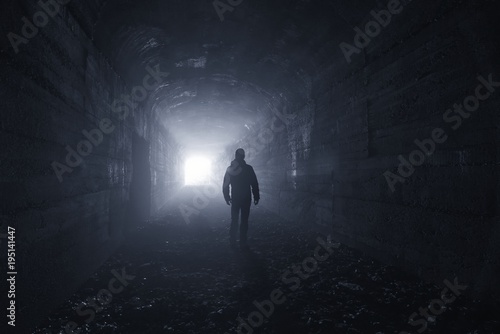 man in a dark concrete tunnel look out the exit - loneliness concept