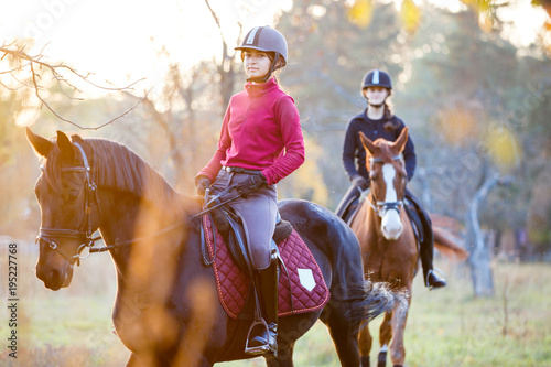 Group of rider girls riding their horses in park. Equestrian recreation activities background with copy space