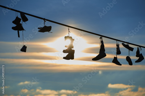 Old Shoes hanging on electrical wire against a sky. Shoe tossing 