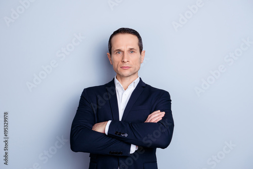 Portrait of thoughtful, concentrated, caucasian man in formalwear, having his arms crossed, standing over gray background