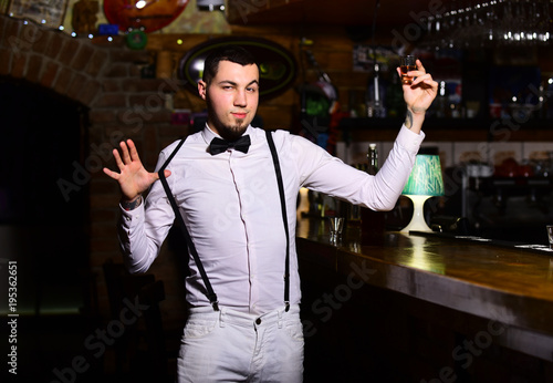 Barman with flirty face in bar drinks shot or liqueur.