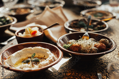 Young happy company of people is eating lebanon food and smokinh shisha. Lebanon cuisine. Traditional meze lunch