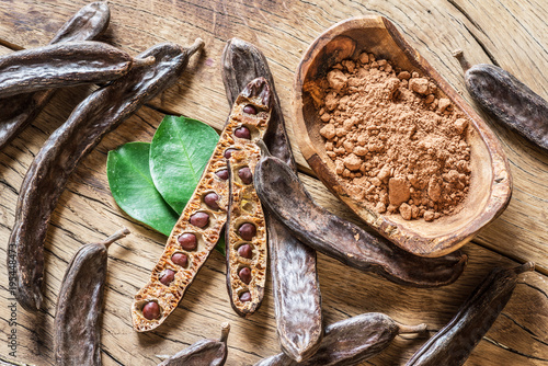 Carob pods and carob beans on the wooden table.