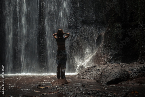 Uoung woman backpacker looking at the waterfall in jungles. Ecotourism concept image travel girl. Bali island, Indonesia.