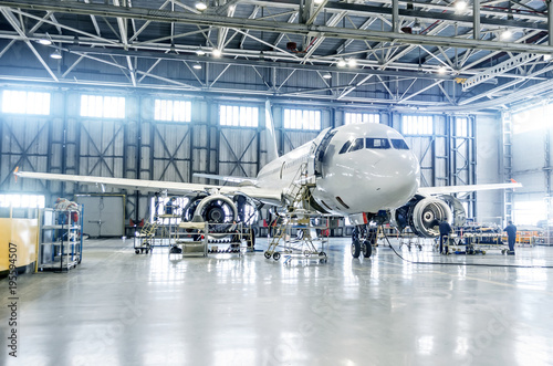 Passenger airplane on maintenance of engine and fuselage check repair in airport hangar.