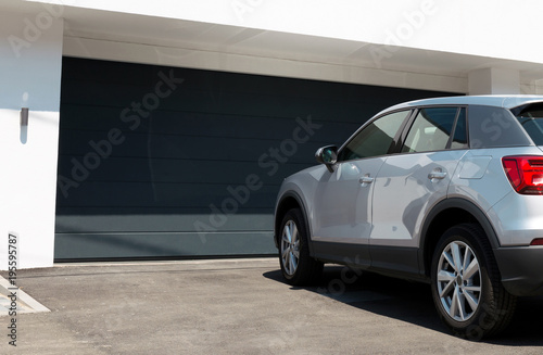 Car in front of modern house waiting to enter in the garage with large garage door