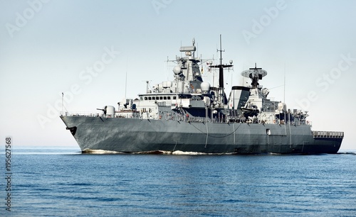 Grey modern warship sailing in still water