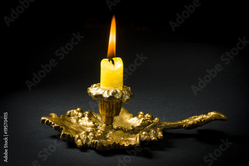 Vintage candlestick with a lit candle on a black background