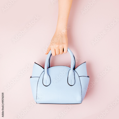 Female hands holds handbag on pink background . Flat lay, top view. Spring fashion concept in pastel colored