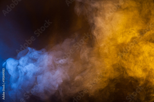 Blue and yellow smoke texture on a black background. Texture and abstract art
