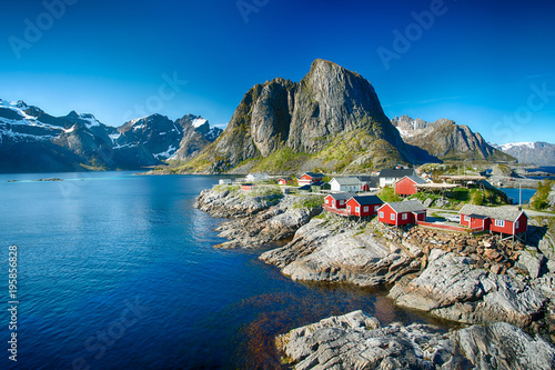 The village of Reine under a sunny, blue sky, with the typical red rorbu houses.
