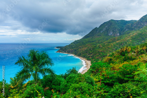 delightful natural wild landscape with rocky mountains overgrown dense green jungle tree, palm and clear azure water of sea ocean