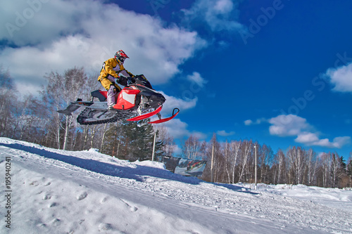 Sport red snowmobile jump. Clear sunny winter day. Concept quick movement.