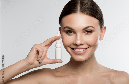 This spray will cure runny nose. Portrait of cheerful young woman is holding medical treatment and smiling. Isolated