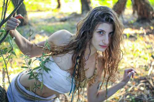 Curious pagan girl looking through the branches into the camera