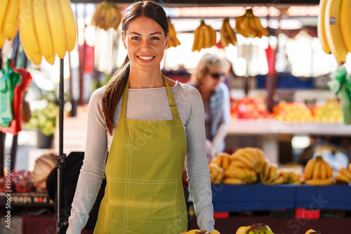 Portrait of young saleswoman on fruit market .