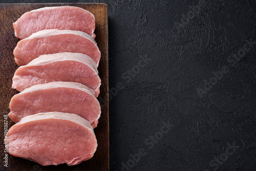 Raw sliced pork loin on a dark background. Fresh meat.