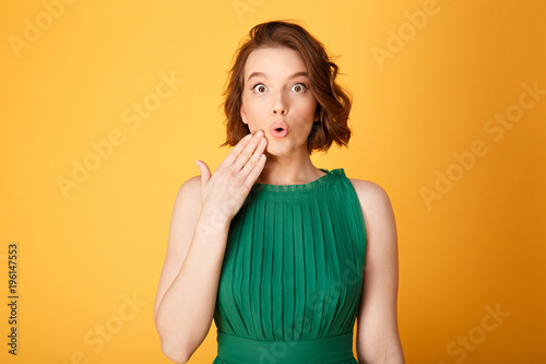 portrait of young surprised woman isolated on orange