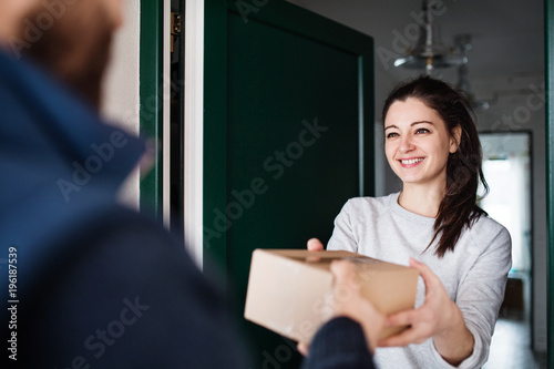 Woman receiving parcel from delivery man at the door.