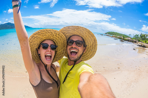 Crazy couple in love having fun taking a selfie at a tropical beach at holiday
