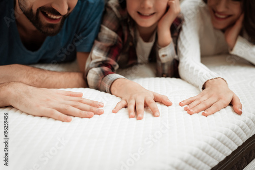 Young couple together with their young son test material of mattress for a touch.