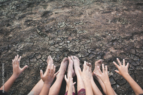 Feet and hand of children praying for the rain on cracked dry ground .concept hope and drought