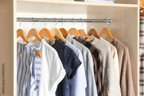 Hangers with different clothes in wardrobe closet