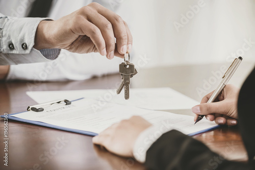 Young woman is signing financial contract with male realtor