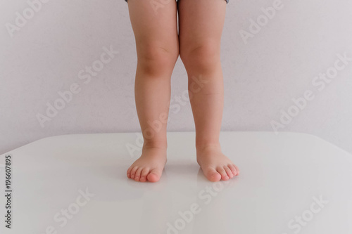 Low section of baby boy in diaper standing isolated on blue background